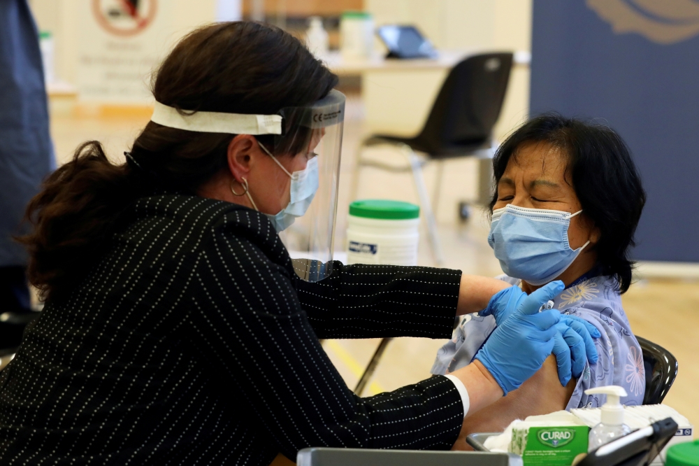 A healthcare worker administers a Pfizer/BioNTEch coronavirus disease (COVID-19) vaccine to personal support worker Anita Quidangen at The Michener Institute, in Toronto, Canada December 14, 2020. REUTERS/Carlos Osorio