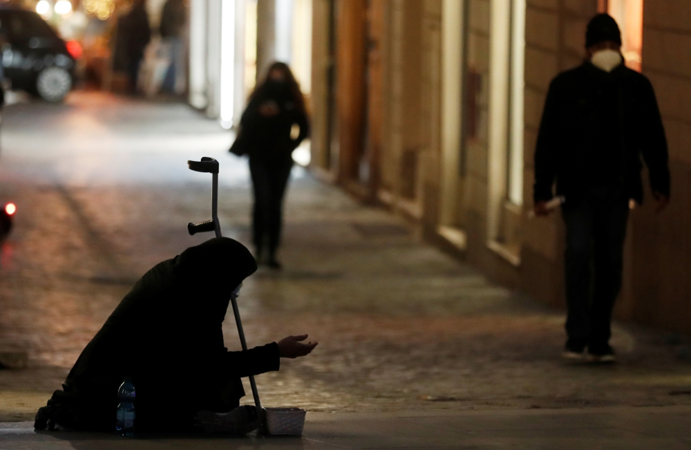 A woman begs for money near Spanish Steps as the government prepares to bring in further restrictions over the Christmas period during the spread of the coronavirus disease (COVID-19) in Rome, Italy December 14, 2020. REUTERS/Yara Nardi
