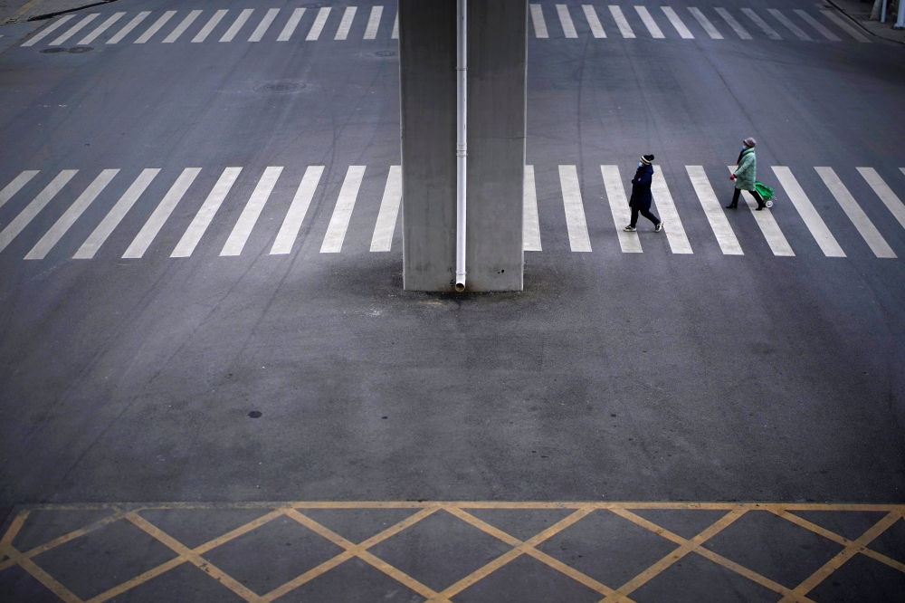 People wearing masks walk across a street, almost a year after the start of the coronavirus disease (COVID-19) outbreak, in Wuhan, Hubei province, China December 17, 2020. REUTERS/Aly Song