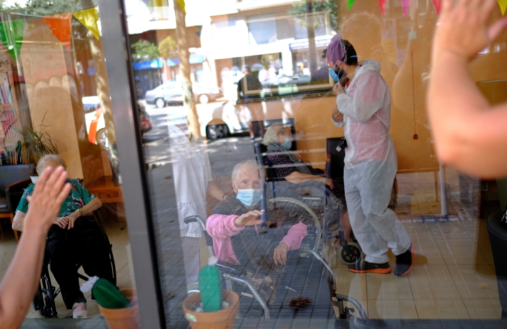 File photo: Josefa Velasco, 94, who overcame the coronavirus disease (COVID-19) and lives in a care home, waves goodbye to her relatives after they talk through a glass front at the Centre Parc nursing home in Barcelona, Spain August 27, 2020. Reuters/Nac