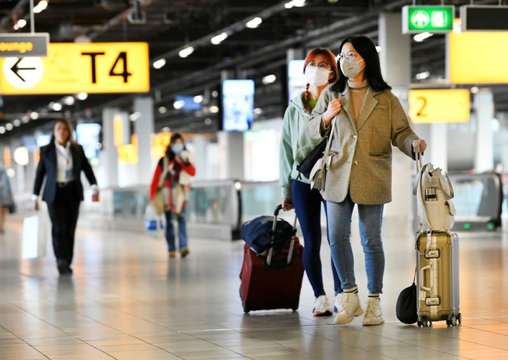 People wearing protective face masks stand, as Schiphol Airport reduces its flights due to the coronavirus disease (COVID-19) outbreak, in Amsterdam, Netherlands April 2, 2020. REUTERS/Piroschka van de Wouw