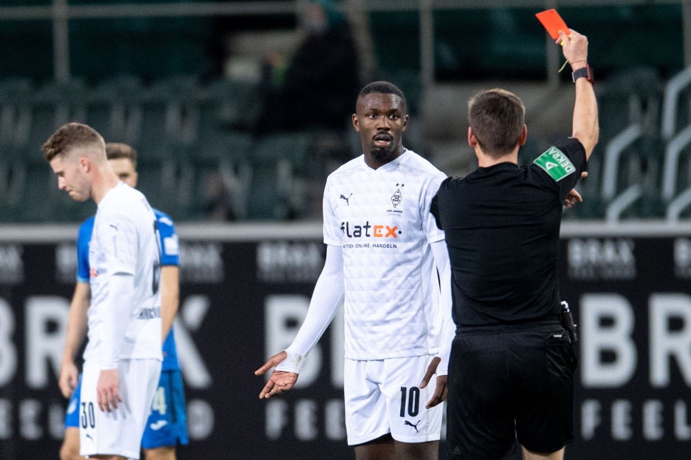 Borussia Moenchengladbach's Marcus Thuram is shown a red card by the referee Pool via REUTERS/Marius Becker