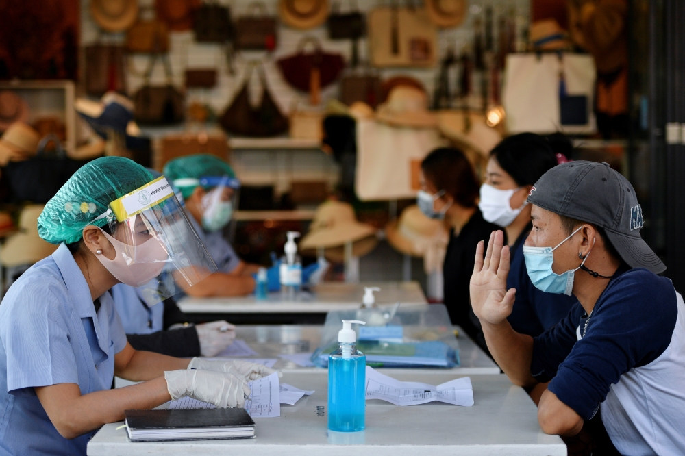 Migrant workers talk with the public health authorities for a COVID-19 investigation at a fresh market, amid the coronavirus disease (COVID-19) outbreak, in Bangkok, Thailand, December 22, 2020. REUTERS/Chalinee Thirasupa