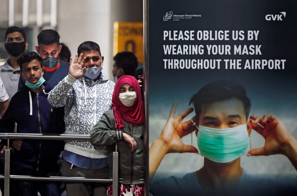 People wearing protective face masks wait for passengers to arrive at Chhatrapati Shivaji Maharaj International Airport after India cancelled all flights from the UK over fears of a new strain of the coronavirus disease (COVID-19), in Mumbai, India, Decem