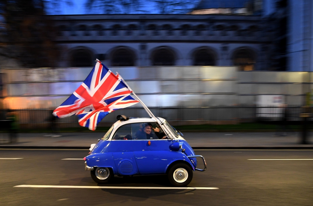 A man waves Union flags from a BMW Isetta in central London. (AFP / DANIEL LEAL-OLIVAS)