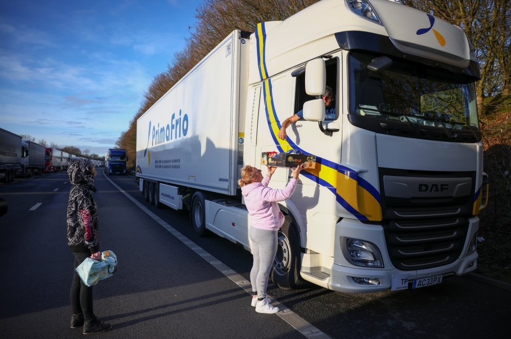 A woman hands out donated food to a lorry driver on the outskirts of Ashford, amid the coronavirus disease (COVID-19) outbreak, December 25, 2020. (REUTERS/Henry Nicholls)