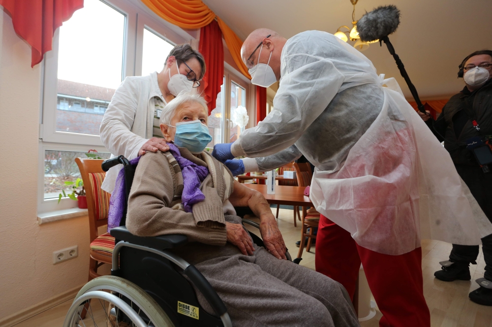 Edith Kwoizalla, 101 years old, receives the first vaccination against the novel coronavirus COVID-19 by Pfizer and BioNTech from Doctor Bernhard Ellendt (R) in a senior care facility in Halberstadt (Seniorenzentrum Krueger), central northern Germany, on 