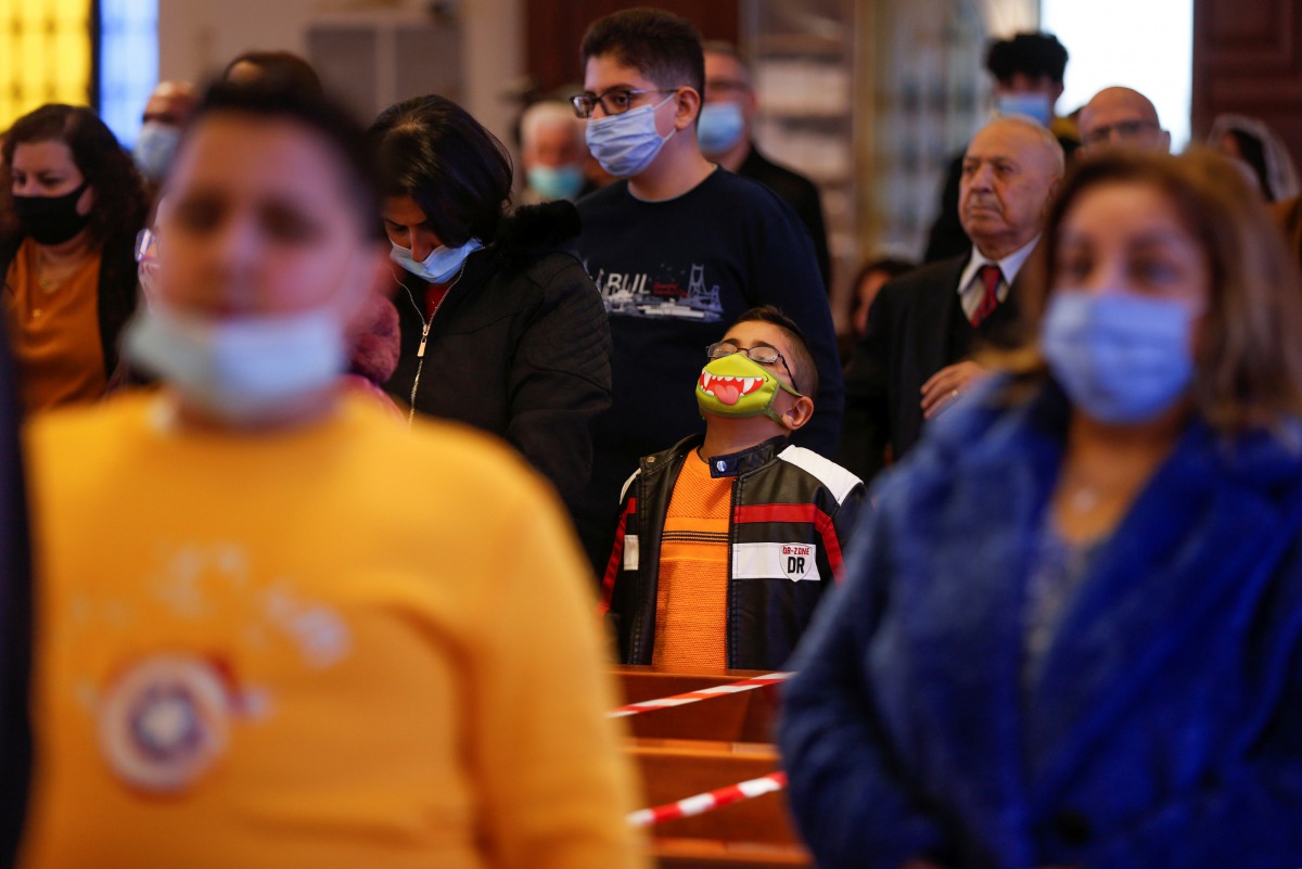 People wearing protective masks and practicing social distancing attend a Mass at Church of the Sacred Heart, as they take part in Christmas celebrations amid the coronavirus disease (COVID-19) pandemic, in Amman, Jordan, December 24, 2020. REUTERS//Muham