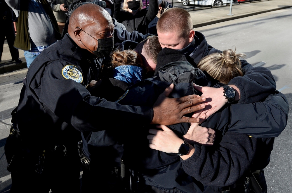 Nashville Metro Police Chief John Drake (L) and officers Amanda Topping, Michael Sipos, James Luellen, Brenna Hosey, and James Wells embrace after a news conference held to discuss the Christmas Day motor home explosion in Nashville, Tennessee, U.S. Decem