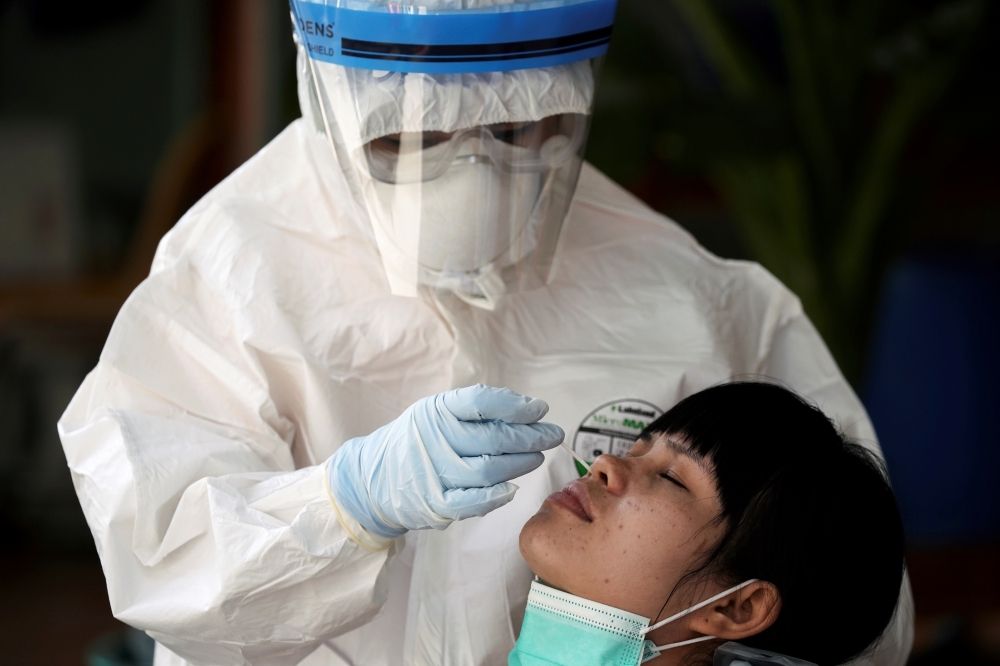 A healthcare worker takes a nasal swab sample of a migrant worker for a COVID-19 test at a migrant community, amid the coronavirus disease (COVID-19) outbreak, in Samut Sakhon province, in Thailand, December 20, 2020. REUTERS/Athit Perawongmetha/File Phot