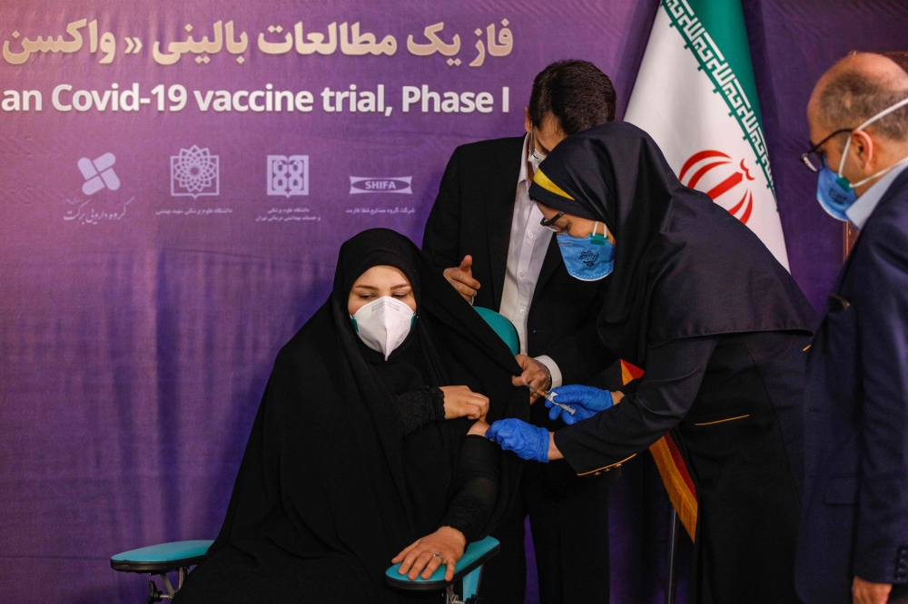 A woman receives an injection during the first trial phase of a locally-made Iranian vaccine for COVID-19 coronavirus disease in Iran's capital Tehran on December 29, 2020. / AFP 