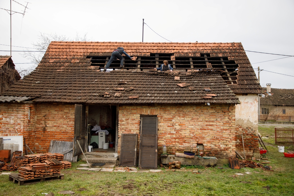 People repair the roof of a damaged house after a 5.2 magnitude earthquake, in Brest Pokupski village, Croatia, December 28, 2020. REUTERS/Antonio Bronic