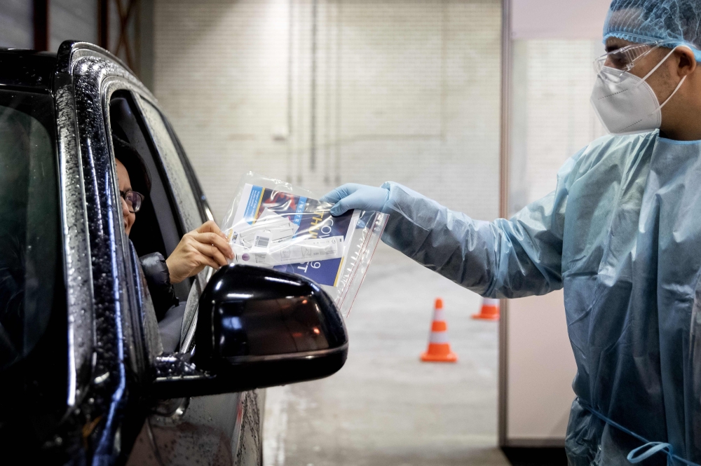 A car driver receives a self-test kit as he must answers questions to the medical staff, at a Covid-19 test location in Tilburg, on December 23, 2020. - Netherlands OUT / AFP / ANP / Koen van Weel