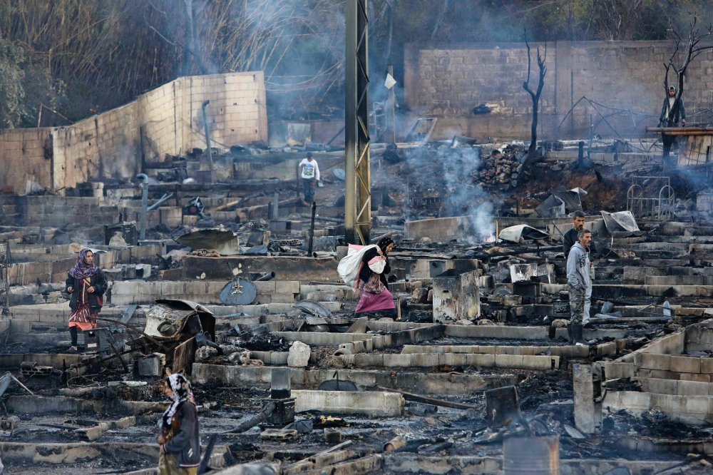 Syrian refugees salvage belongings from the wreckage of their shelters at a camp set on fire overnight in the northern Lebanese town of Bhanine on December 27, 2020, following a fight between members of the camp and a local Lebanese family. AFP / Ibrahim 