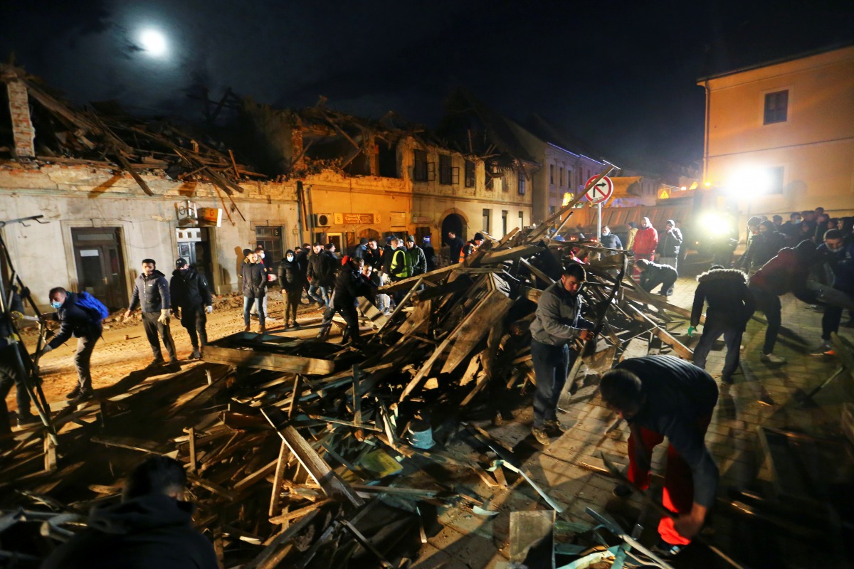 People clean debris from a street after an earthquake, in Petrinja, Croatia December 29, 2020. REUTERS/Antonio Bronic

