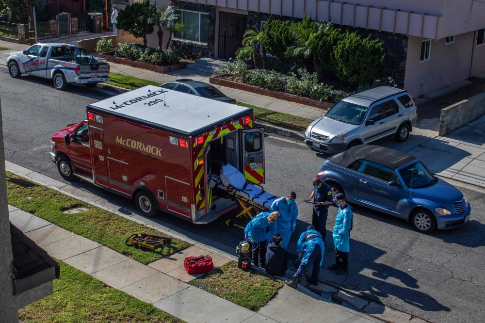County of Los Angeles paramedics examine a potential Covid-19 patient sitting on the sidewalk before transporting him to a hospital in Hawthorne, California on December 29, 2020.  AFP / Apu GOMES