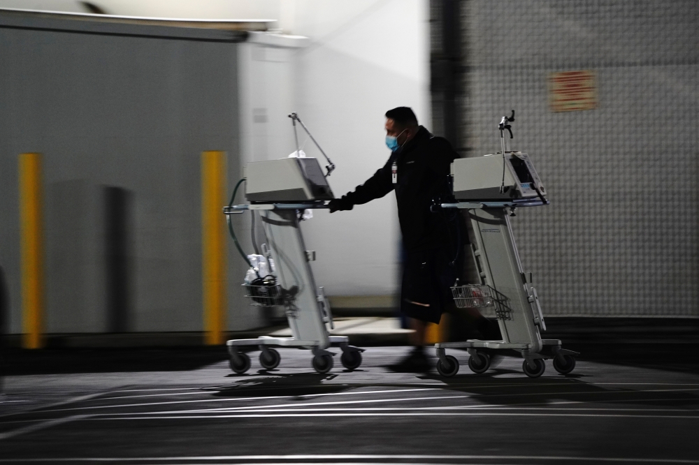 A hospital worker pushes two Computer on Wheels (COW) workstations outside the emergency room at the Community Hospital of Huntington Park during a surge in positive coronavirus cases in Huntington Park, California, U.S. December 29, 2020. REUTERS/Bing Gu