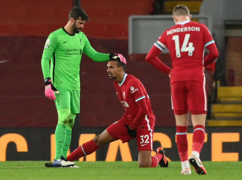 Liverpool's Brazilian goalkeeper Alisson Becker (L) stands with injured Liverpool's German-born Cameroonian defender Joel Matip (C) during the English Premier League football match between Liverpool and West Bromwich Albion at Anfield in Liverpool, north 