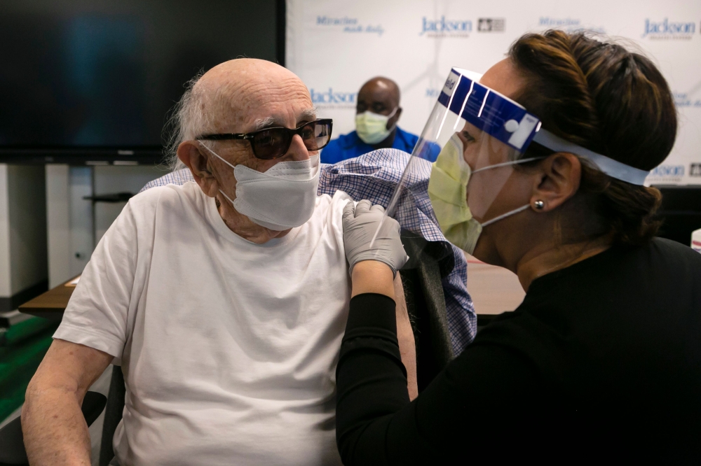 Norman G. Einspruch, 88, a cardiology patient at Jackson Memorial Hospital, talks with a nurse after receiving a Pfizer-BioNtech Covid-19 vaccine at Christine E. Lynn Rehabilitation Center, in Miami, Florida on December 30, 2020. / AFP / Eva Marie UZCATEG