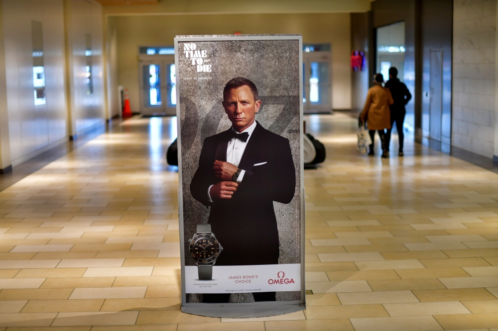 Shoppers walk past an advertisement for the upcoming James Bond film 