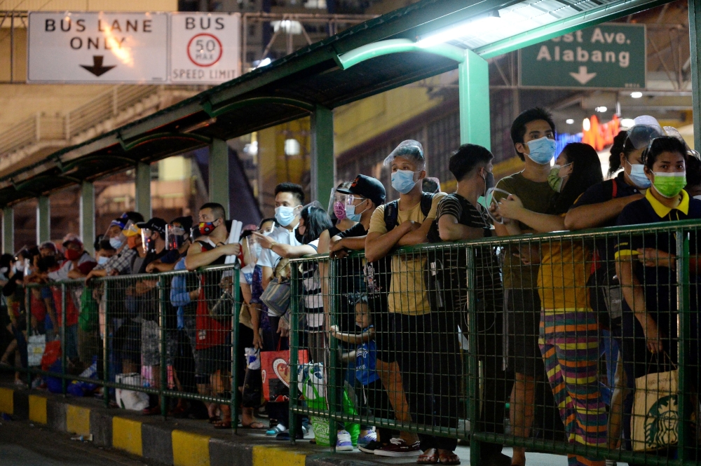 People wearing face masks and face shields as protection against the coronavirus disease (Covid-19) queue at a bus stop, in Quezon City, Metro Manila, Philippines, December 23, 2020. Reuters/Lisa Marie David/File Photo