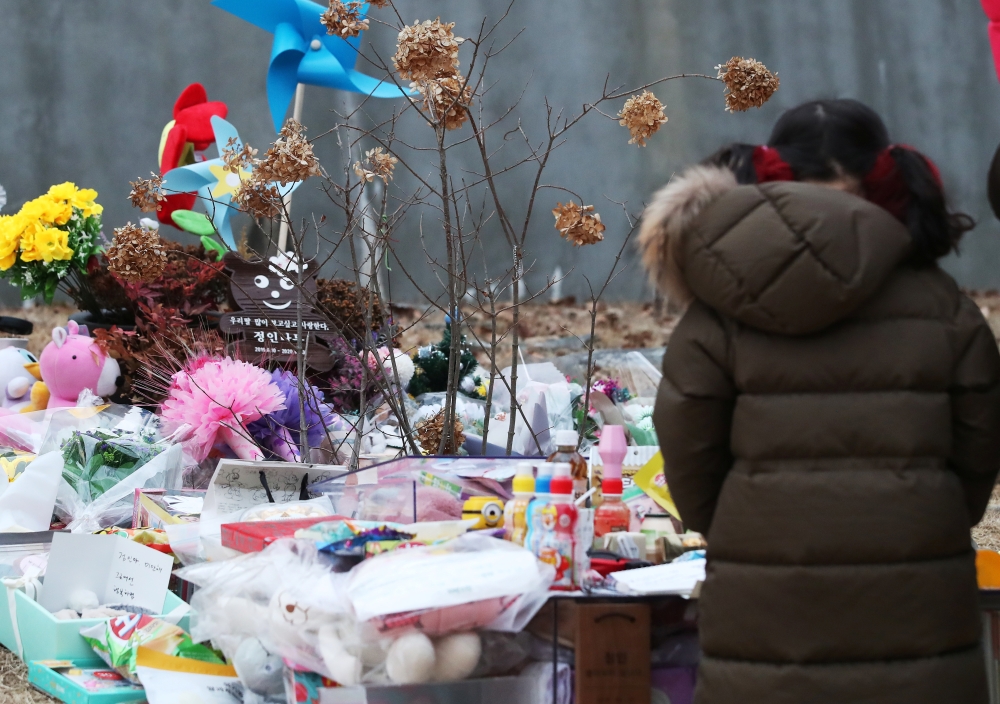A girl mourns at a tomb of 16-month-old girl named Jeong-in who died after having been abused by her adoptive mother, in Yangpyeong, South Korea, January 4, 2021. Yonhap via Reuters 