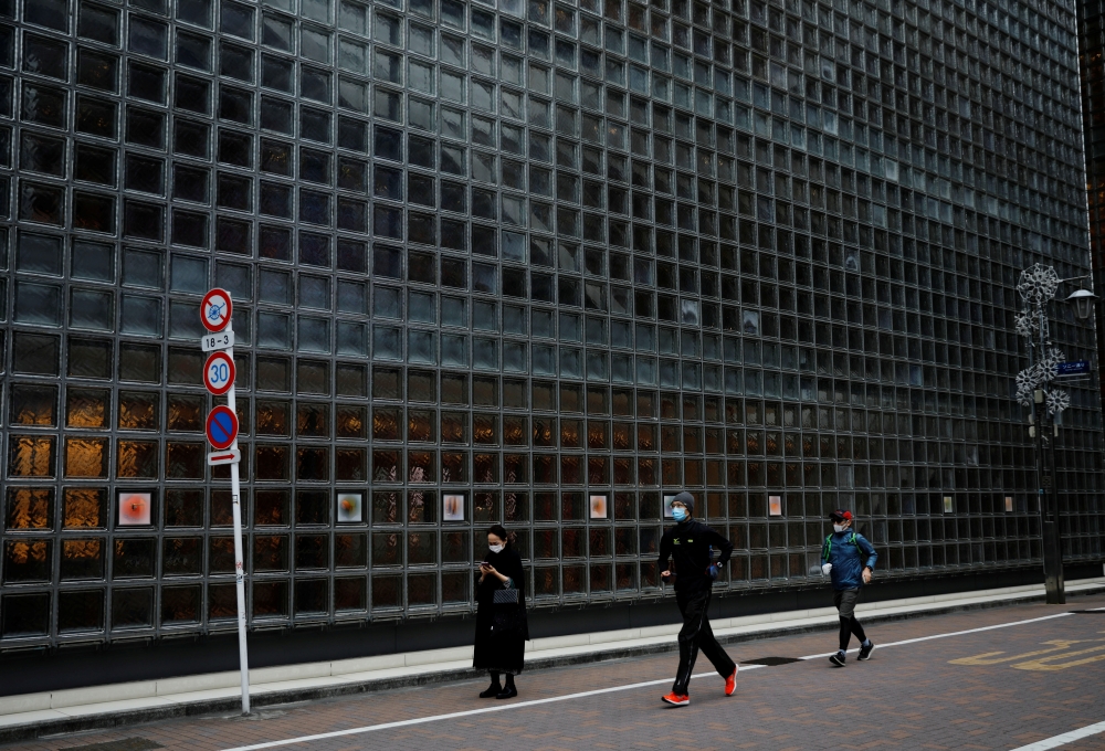 Joggers wearing protective masks, following the coronavirus disease (COVID-19) outbreak, run at a shopping district in Tokyo, Japan, January 6, 2021. REUTERS/Kim Kyung-Hoon