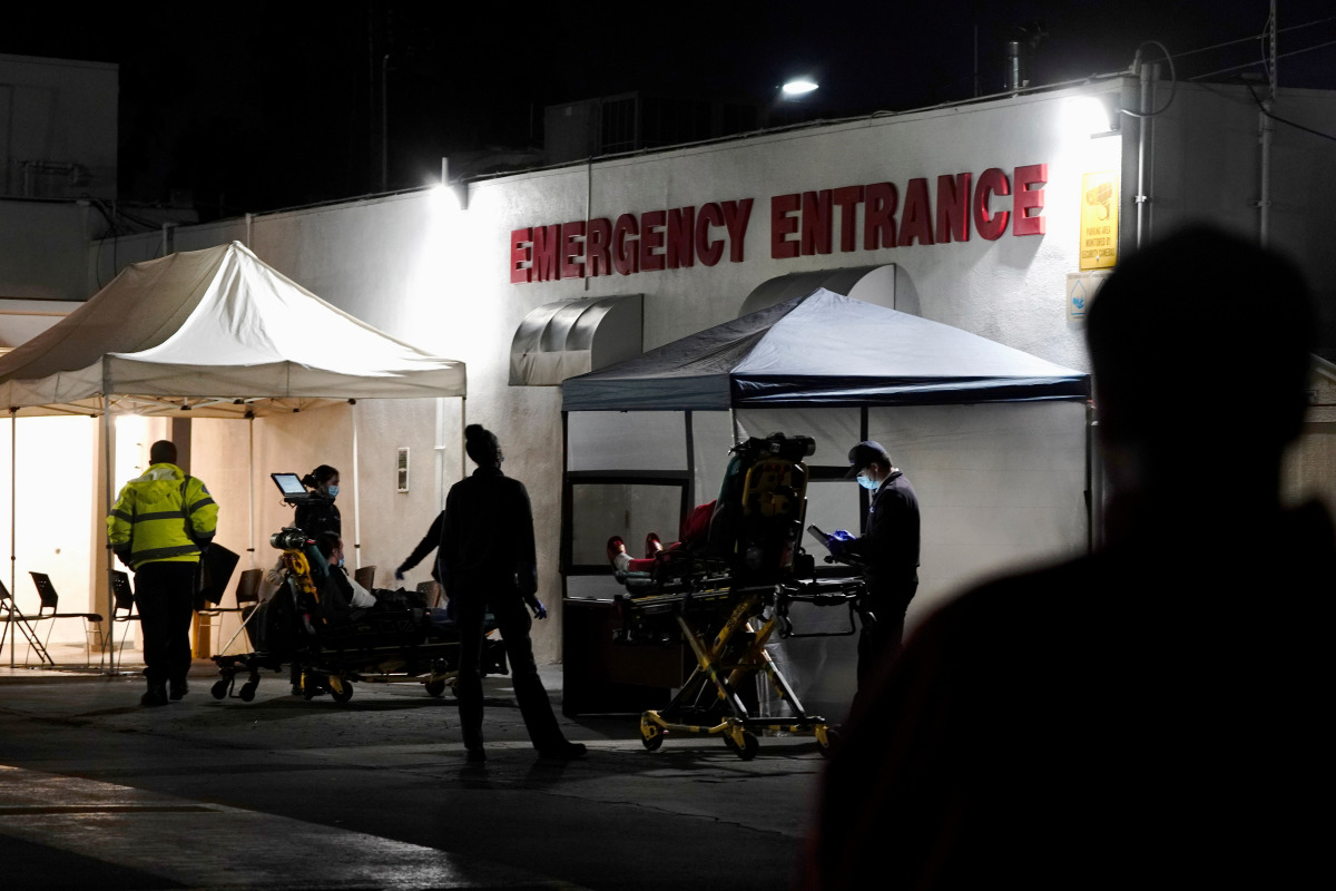 FILE PHOTO: Emergency medical technicians (EMTs) and healthcare workers treat patients outside the emergency room at the Community Hospital of Huntington Park during a surge in positive coronavirus disease (COVID-19) cases in Huntington Park, California, 
