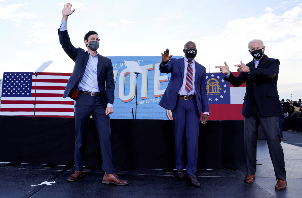 FILE PHOTO: President-elect Joe Biden points to Democratic Senate candidates from Georgia Jon Ossoff  and Raphael Warnock, as he campaigns on their behalf ahead of their January 5 run-off elections, during a drive-in campaign rally in Atlanta, Georgia, Ja