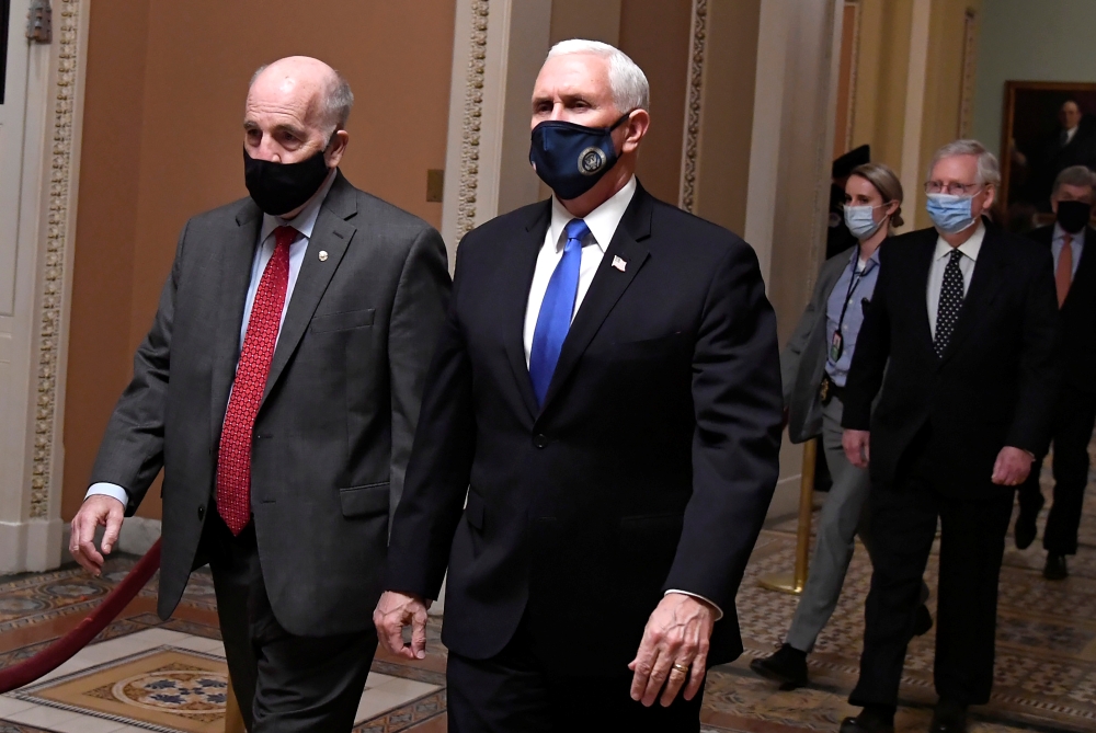 Vice President Mike Pence (R) is escorted by Sgt. at Arms Michael Stenger (L), followed by Senate Majority Leader Mitch McConnell (R-KY) as they walk to the House in the US Capitol to continue a joint session to certify President-elect Joe Biden, in Washi
