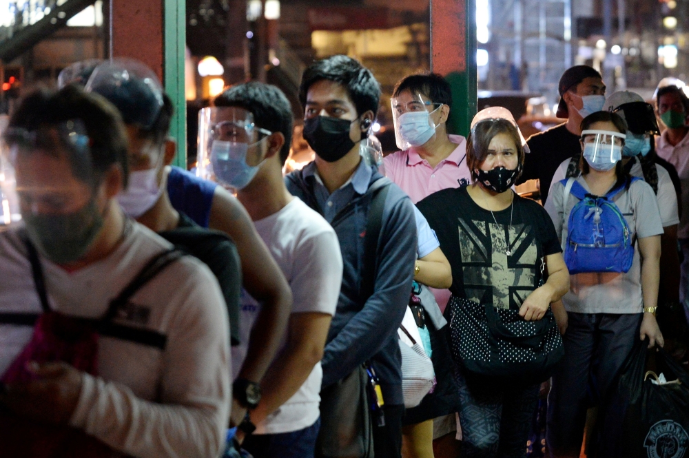 People wearing face masks and face shields as protection against the coronavirus disease (COVID-19) queue at a bus stop, in Quezon City, Metro Manila, Philippines, December 23, 2020. REUTERS/Lisa Marie David/File Photo