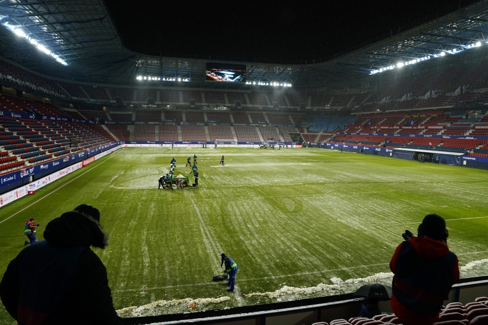 Grounds staff clear snow off the pitch before the match REUTERS/Vincent West
