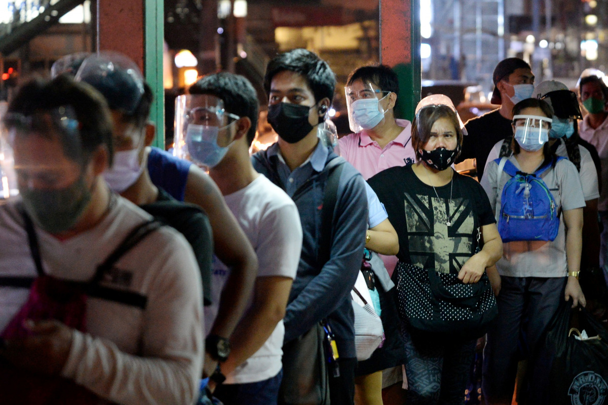FILE PHOTO: People wearing face masks and face shields as protection against the coronavirus disease (COVID-19) queue at a bus stop, in Quezon City, Metro Manila, Philippines, December 23, 2020. REUTERS/Lisa Marie David/File Photo
