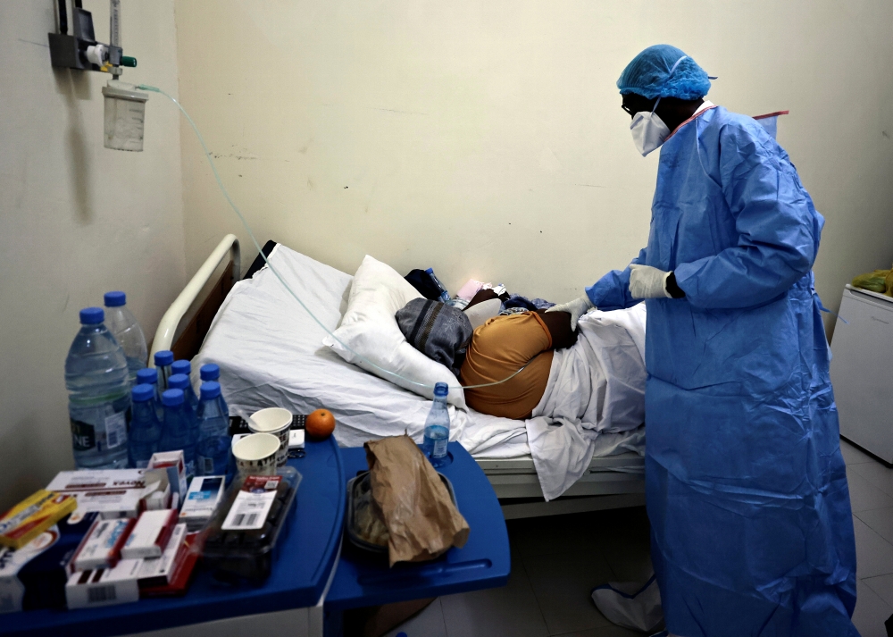 Professor Moussa Seydi, wearing his personal protective equipment (PPE) talks to a patient, who is suffering from coronavirus disease at the infectious diseases department of the University Hospital Fann, in Dakar, Senegal January 7, 2021. Reuters/ Zohra 
