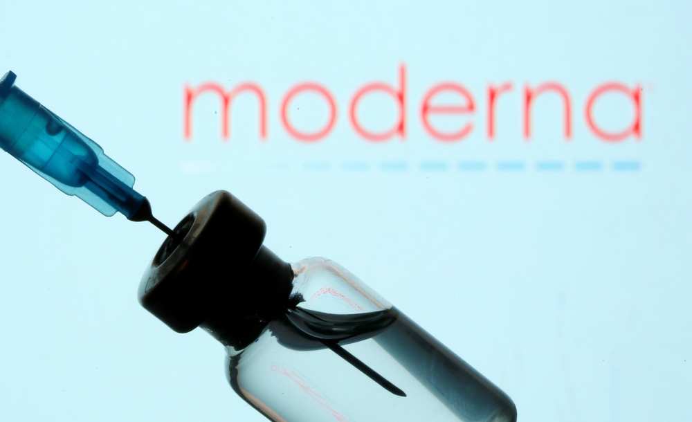 A vial and sryinge are seen in front of a displayed Moderna logo in this illustration taken January 11, 2021. REUTERS/Dado Ruvic/Illustration