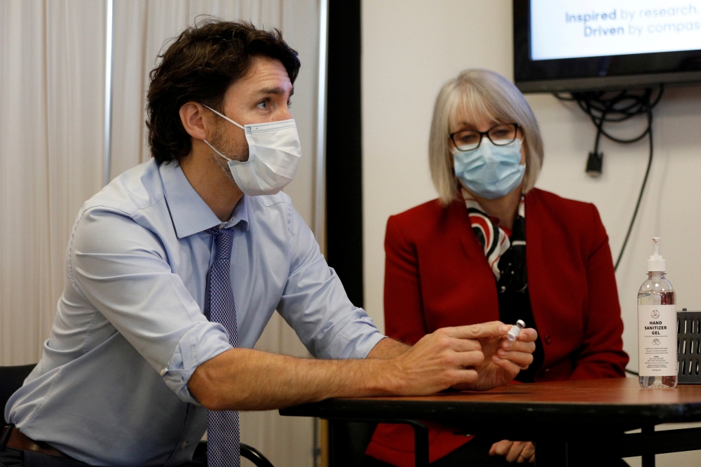 Canada's Prime Minister Justin Trudeau, with Minister of Health Patty Hajdu, holds an empty COVID-19 vaccine vial after the first vaccinations were given at the Civic Hospital in Ottawa, Ontario, Canada December 15, 2020. REUTERS/Blair Gable/File Photo
