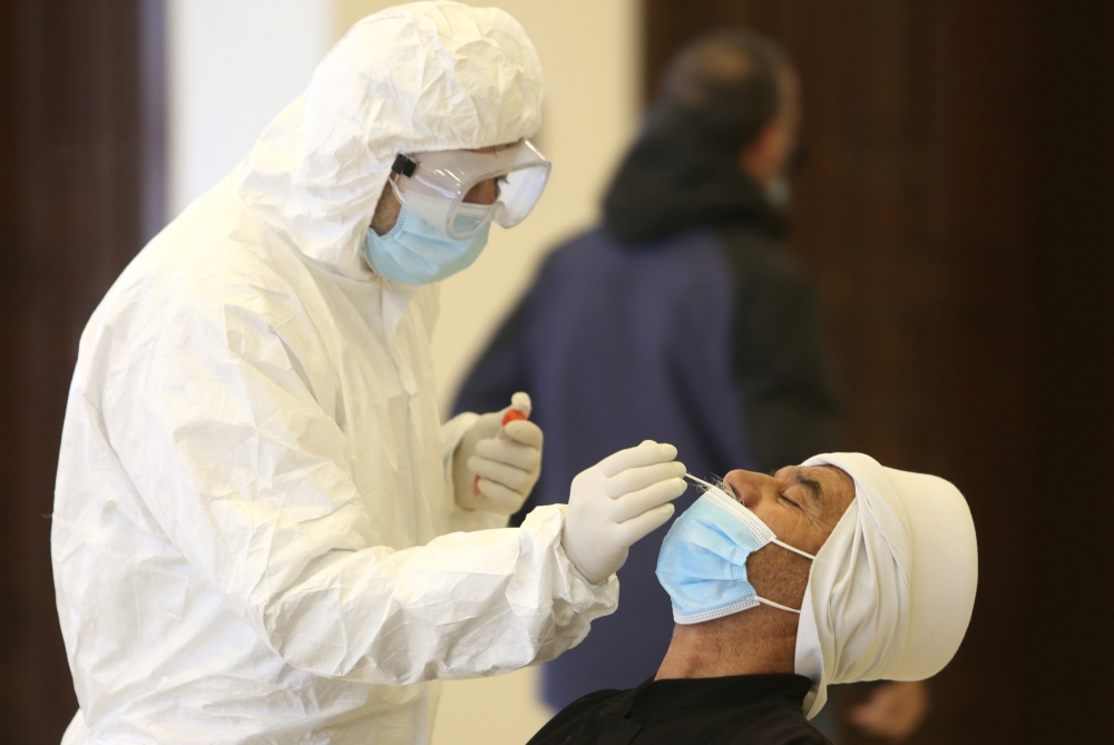 A health worker takes a swab from a man to be tested for coronavirus disease (COVID-19) in the town of Hasbaya, Lebanon, January 16, 2021. REUTERS/Aziz Taher