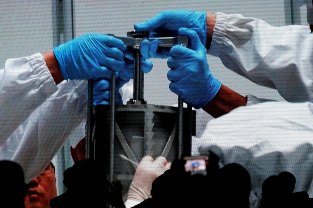 A screen shows footages of researchers holding an equipment carrying lunar sample from Chang'e-5 Mission, during an event on China’s lunar exploration program, at the National Astronomical Observatories of Chinese Academy of Sciences (CAS), in Beijing, Ch