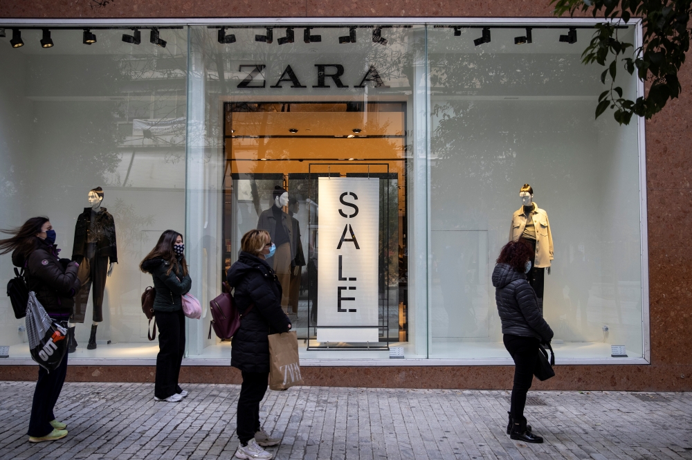People wearing protective face masks apply social distancing as they wait to enter a shop on the first day of the re-opening of retail stores, amid the coronavirus disease (COVID-19) pandemic, in Athens, Greece, January 18, 2021. REUTERS/Alkis Konstantini