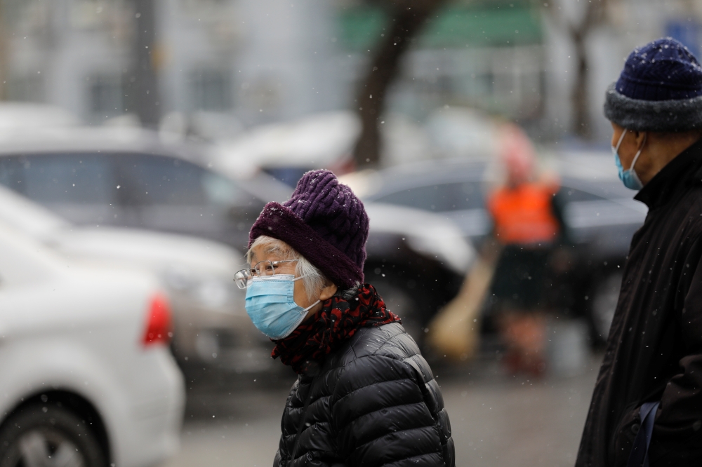 People wearing face masks following the coronavirus disease (COVID-19) outbreak are seen on a snowy day in Beijing, China January 19, 2021. REUTERS/Tingshu Wang
