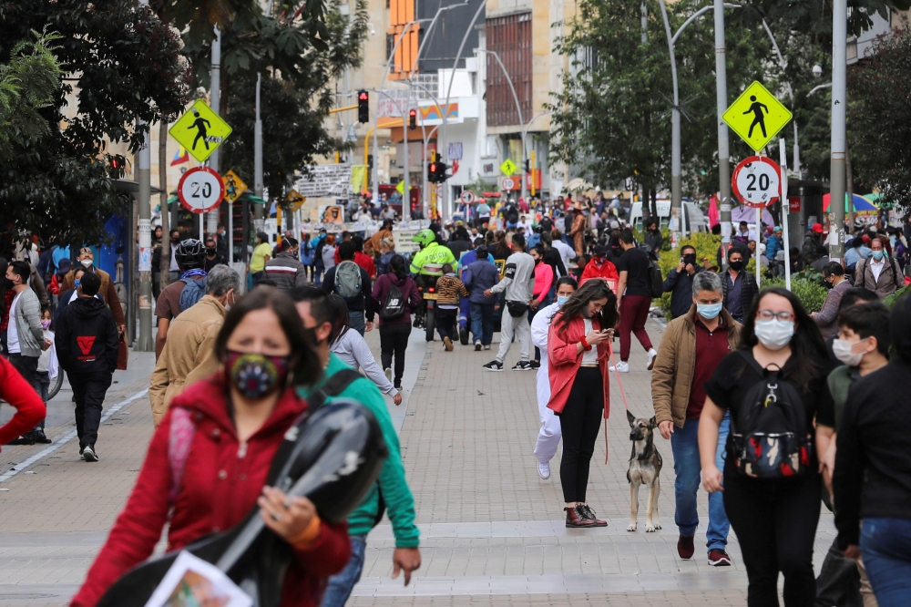 People wearing face masks walk down a street before the start of a mandatory total isolation decreed by the mayor's office, amidst an outbreak of the coronavirus disease (COVID-19), in Bogota, Colombia January 7, 2021. REUTERS/Luisa Gonzalez/File Photo