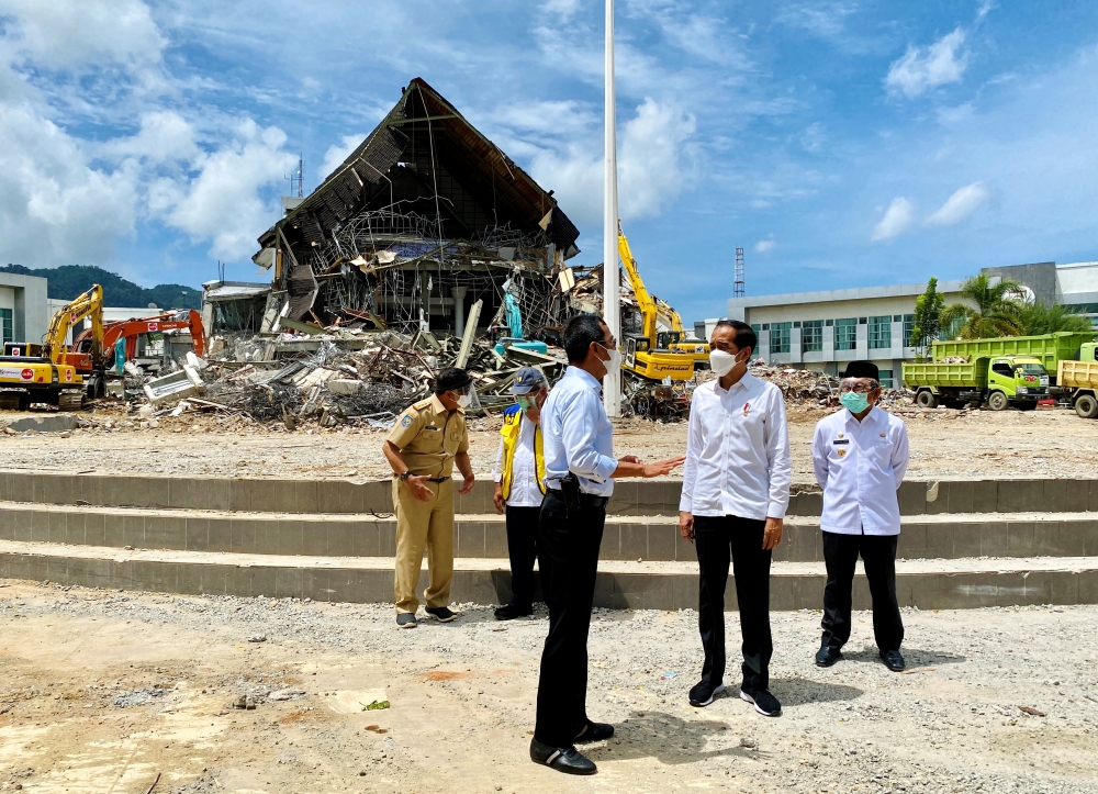Indonesian President Joko Widodo talks with an official during a visit inspecting the area affected by the earthquake in Mamuju, West Sulawesi province, Indonesia, January 19, 2021. Courtesy of Indonesia's Presidential Palace/Handout via REUTERS