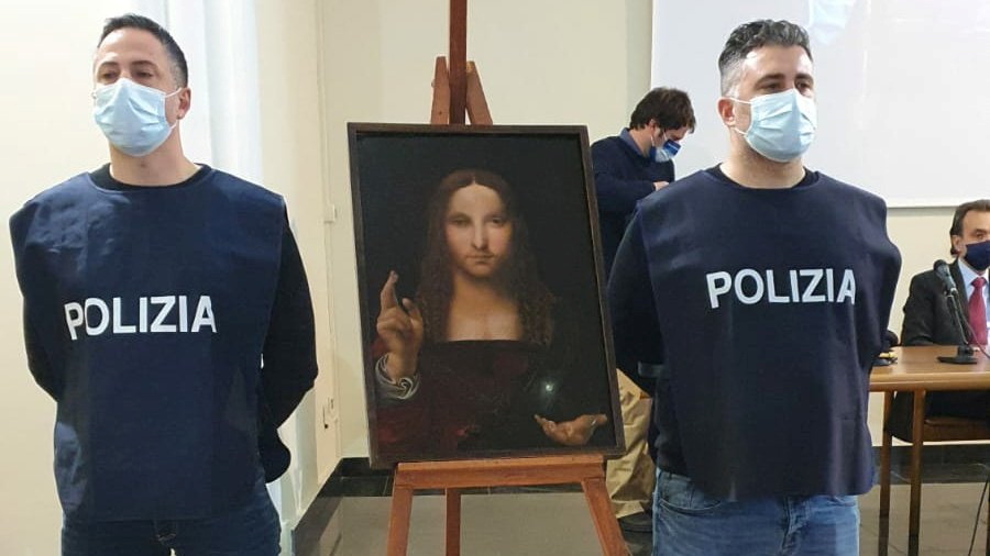 Police officers stand next to a recovered 500-year-old painting titled 'Salvator Mundi' from the school of Leonardo da Vinci, which was stolen from a museum collection in the Basilica di San Domenico Maggiore and was discovered by police in an apartment i