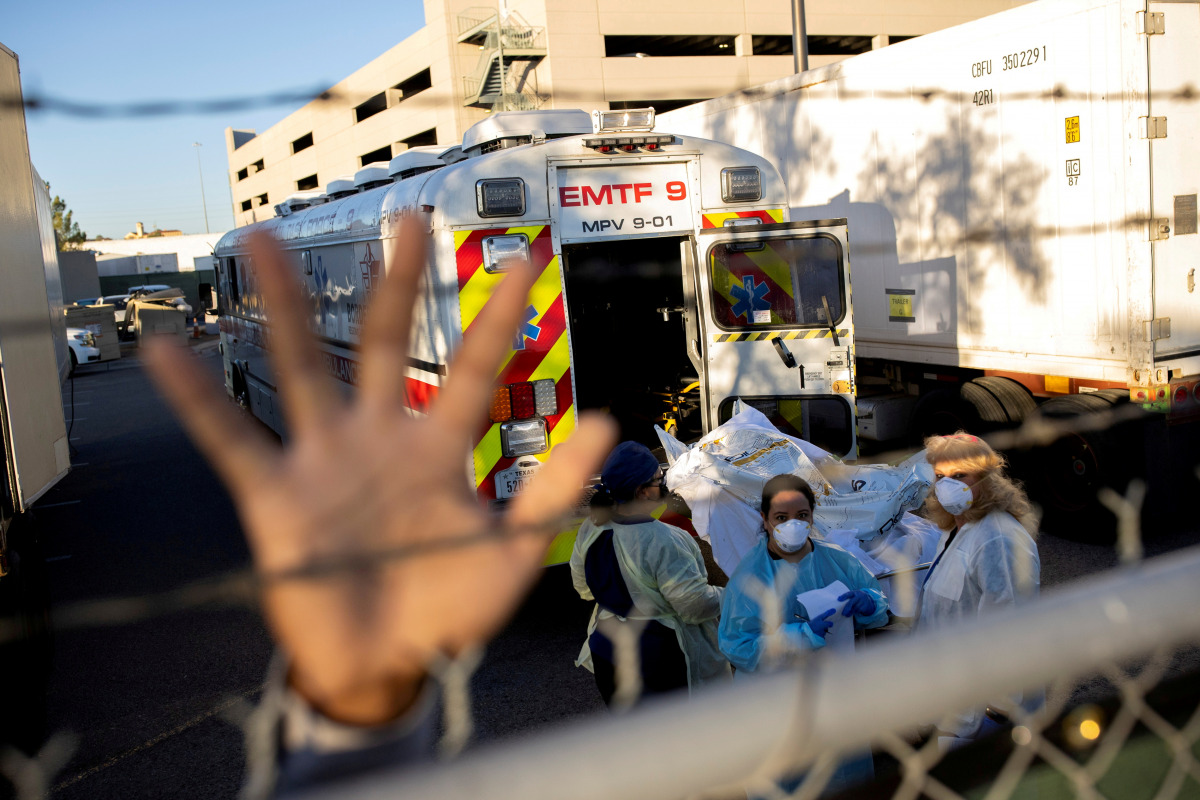 FILE PHOTO: An El Paso County Sheriff's Officer tries to block photographs from being taken as bodies are moved to refrigerated trailers, deployed during a surge of coronavirus disease (COVID-19) deaths, outside the County of El Paso Medical Examiner's Of
