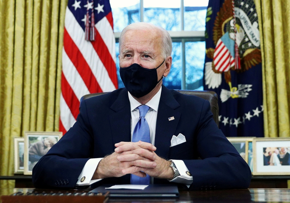 FILE PHOTO: U.S. President Joe Biden signs executive orders in the Oval Office of the White House in Washington, after his inauguration as the 46th President of the United States, U.S., January 20, 2021. REUTERS/Tom Brenner