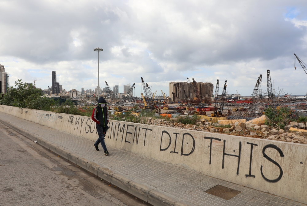 A man wearing a face mask walks near the damaged grain silo, as Lebanon tightened lockdown and introduced a 24-hour curfew to curb the spread of the coronavirus disease (COVID-19) in Beirut, Lebanon, January 15, 2021. REUTERS/Mohamed Azakir
