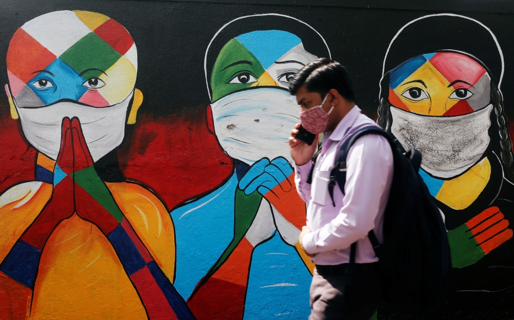 A man walks past a graffiti of people wearing protective masks amidst the spread of Covid-19 on a street in Navi Mumbai, India January 21, 2021. Reuters/Francis Mascarenhas