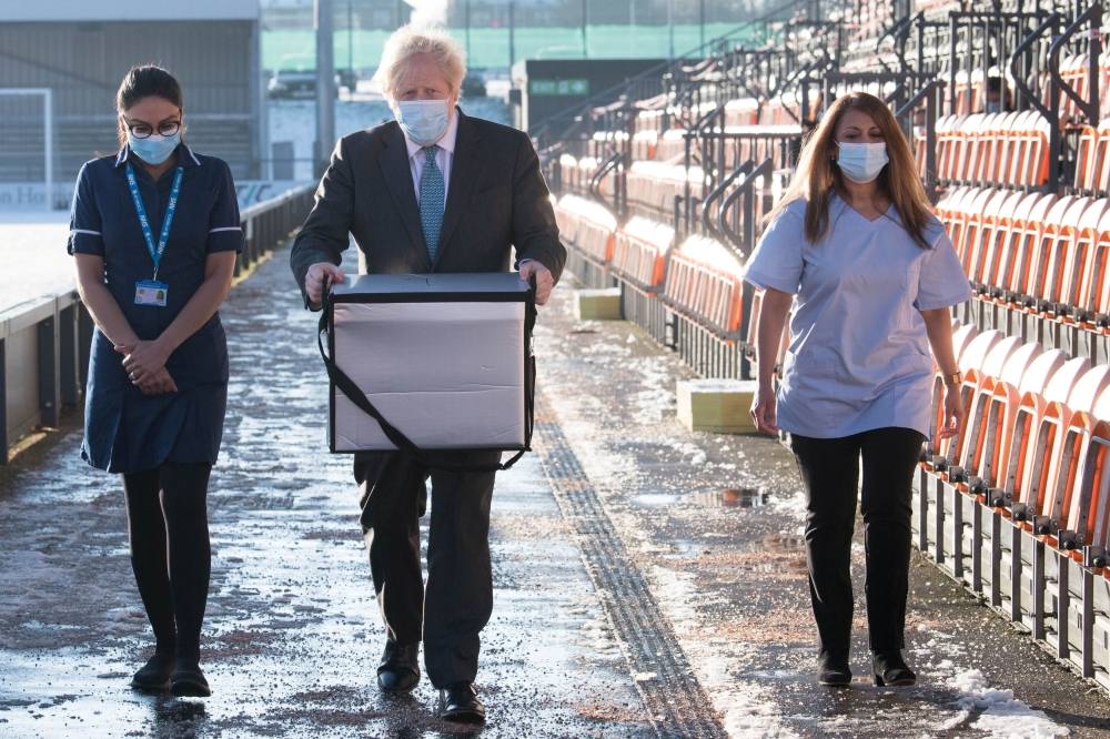 British Prime Minister Boris Johnson loads doses of the Oxford/AstraZeneca COVID-19 vaccine for mobile distribution at Barnet FC's ground, The Hive, which is being used as a coronavirus vaccination centre, in north London, Britain January 25, 2021. Stefan