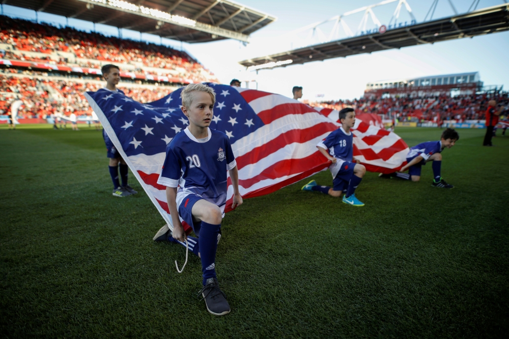 FILE PHOTO: Kids hold an American flag during the national anthems before Toronto FC play D.C. United in their MLS soccer match, at BMO Field, a venue for the 2026 FIFA World Cup, in Toronto, Ontario, Canada, June 13, 2018. REUTERS/Mark Blinch/File Photo