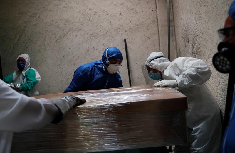 FILE PHOTO: Funeral and crematorium employees work on a coffin carrying the body of a person who died from the coronavirus disease (COVID-19) before its cremation, as the number of deaths continues to rise due to the coronavirus disease (COVID-19) outbrea
